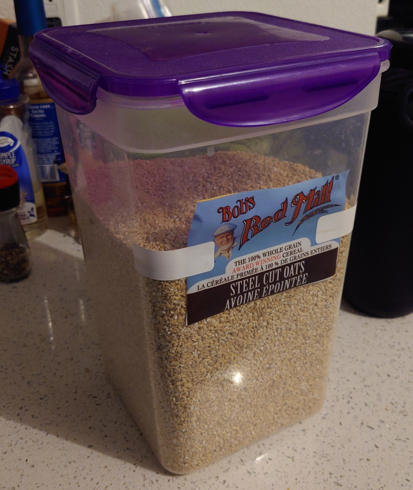 A tall container of steel cut oats with the label taped to the front.